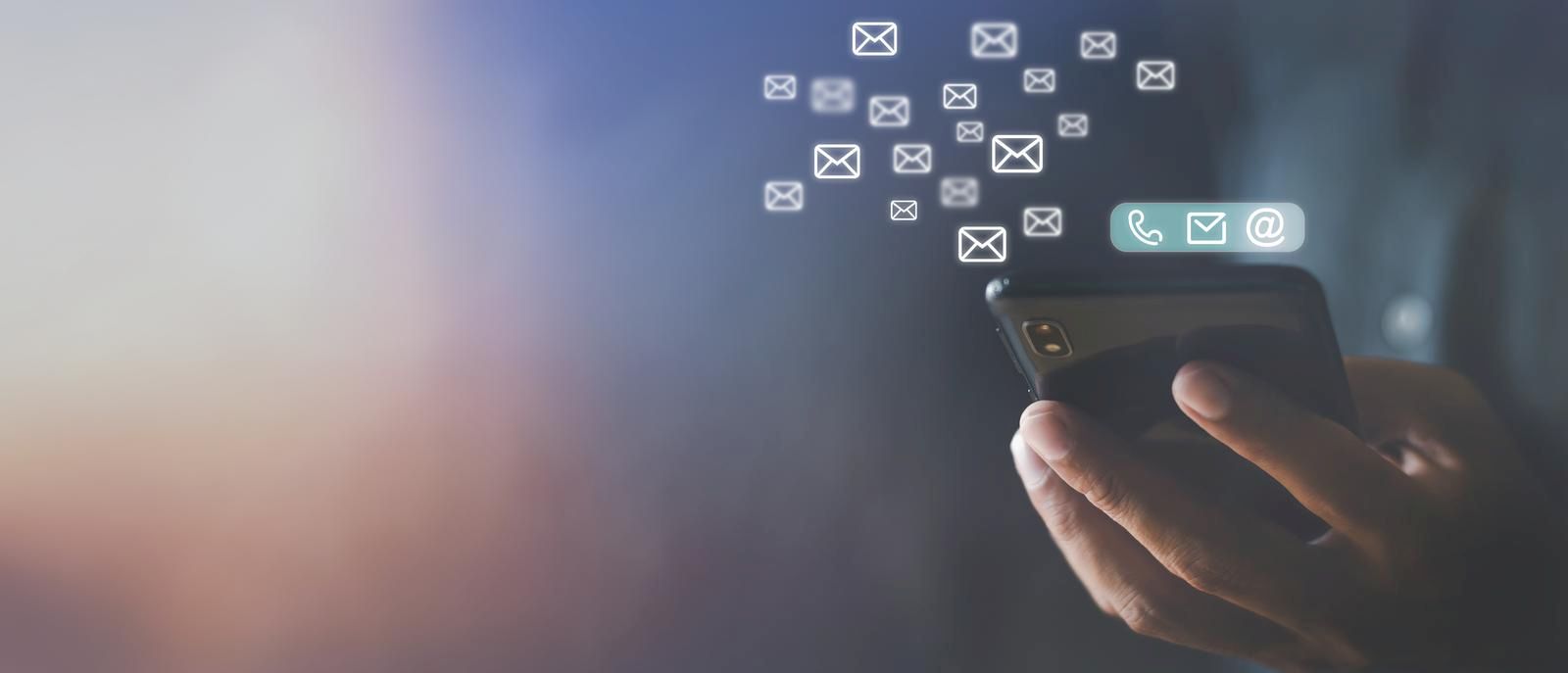 Mão segurando usando telefone celular com ícone de e-mail na tela.